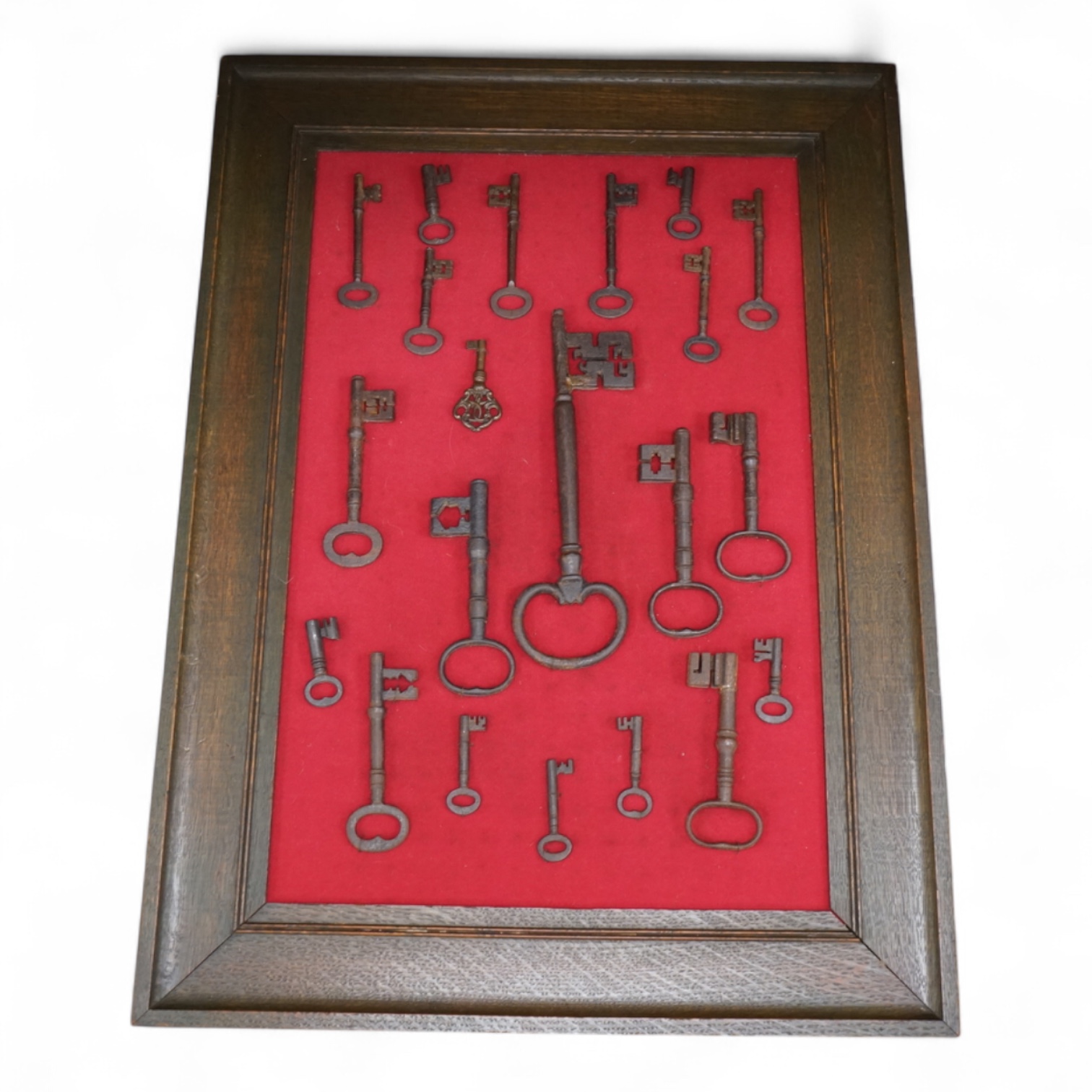 A framed collection of early antique iron keys, largest key 25cm long, board with all keys 66cm high